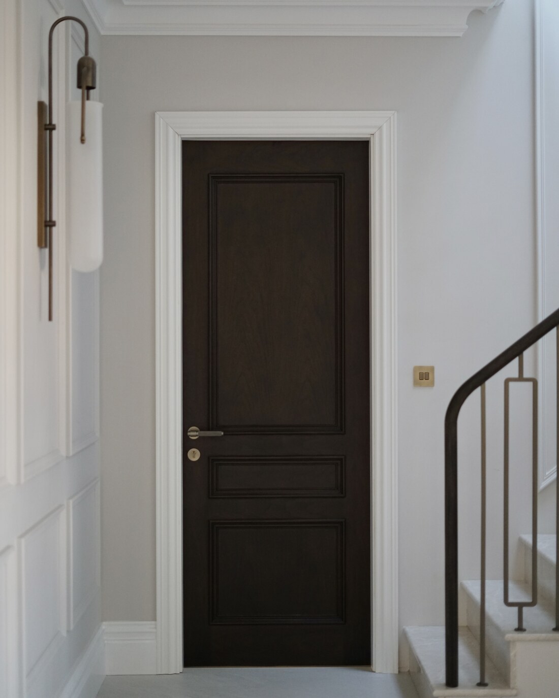 Bespoke panelled door with brass wall light in a residential project